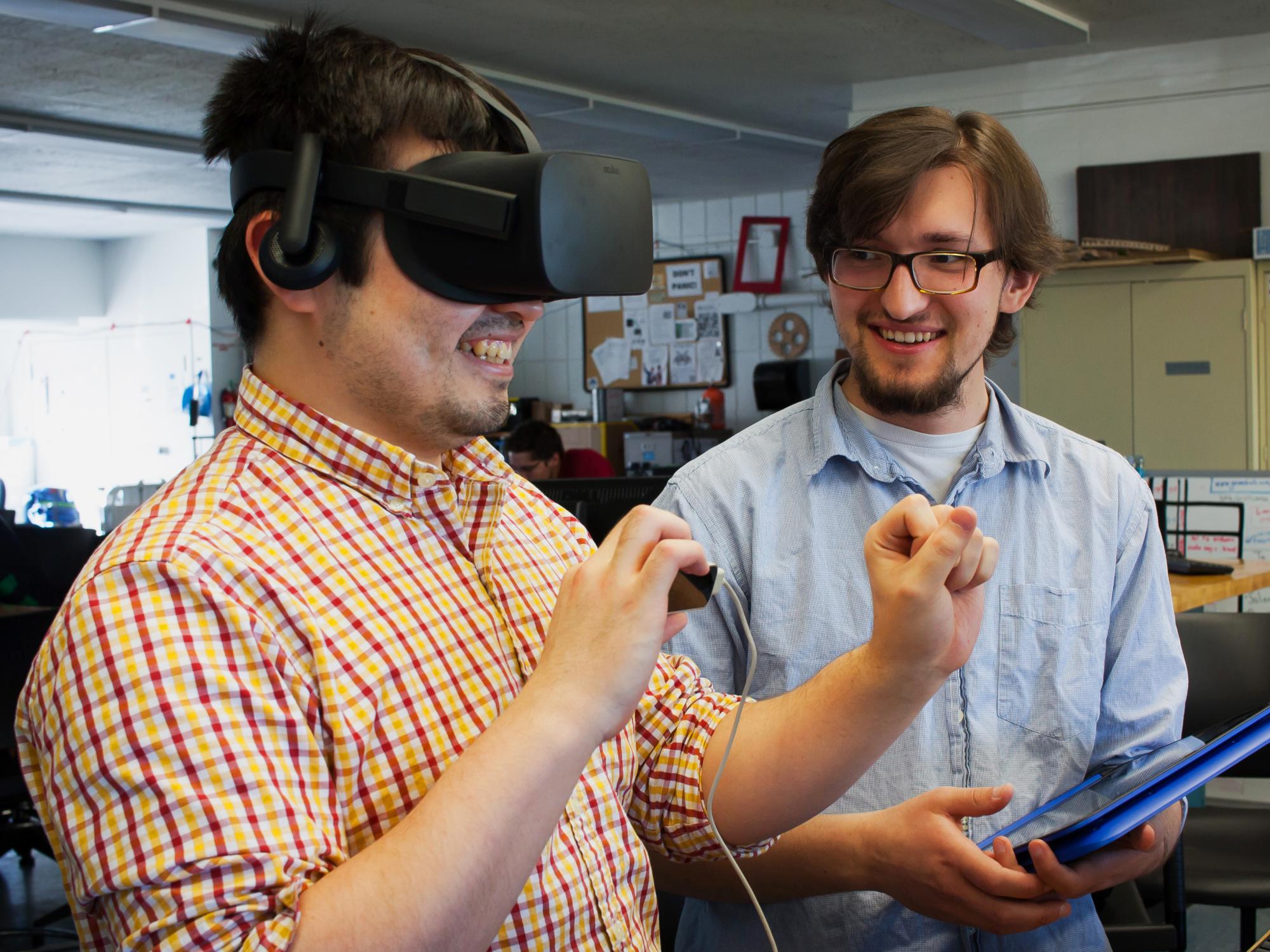 A student watches as another student uses the Oculus Rift virtual reality device