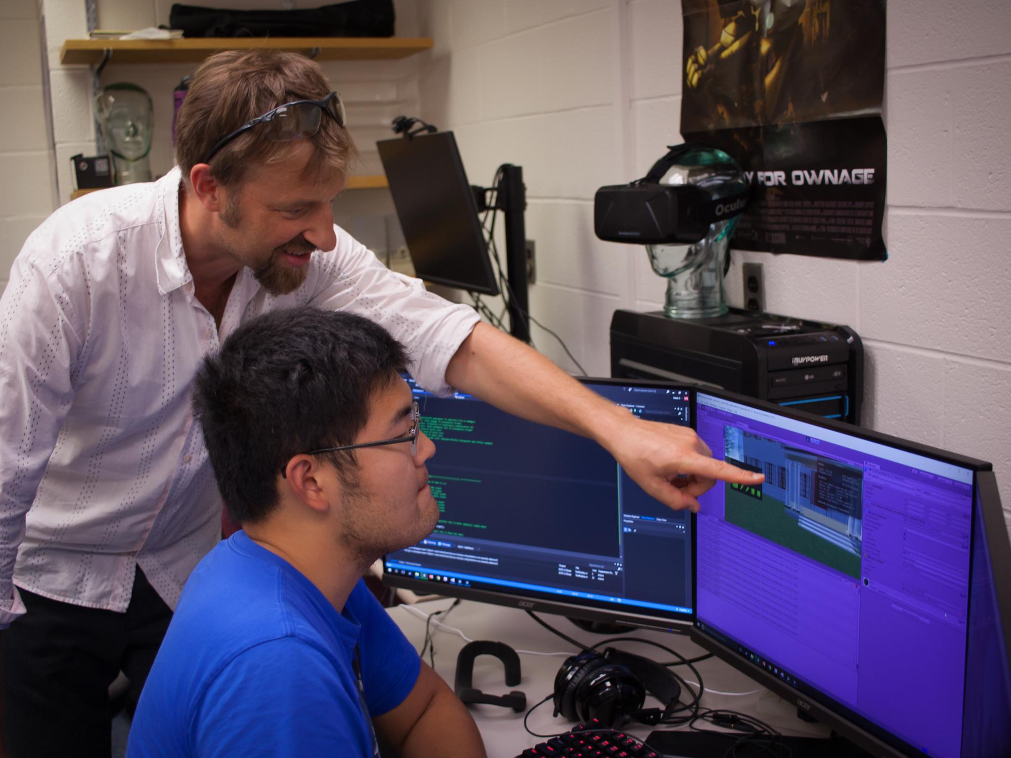 A professor works with a student at a computer. 