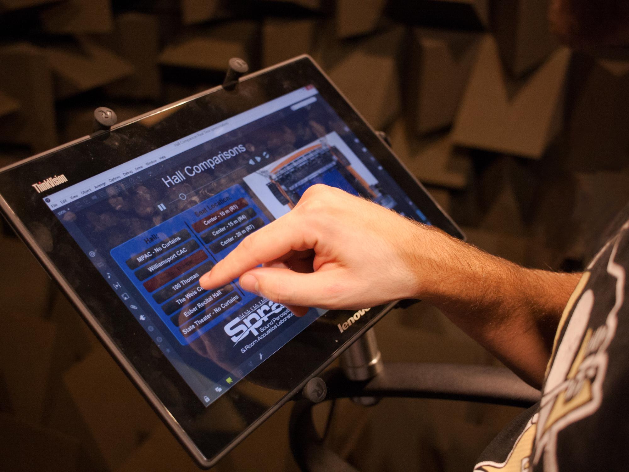 A student uses a tablet displaying a list of concert halls. 