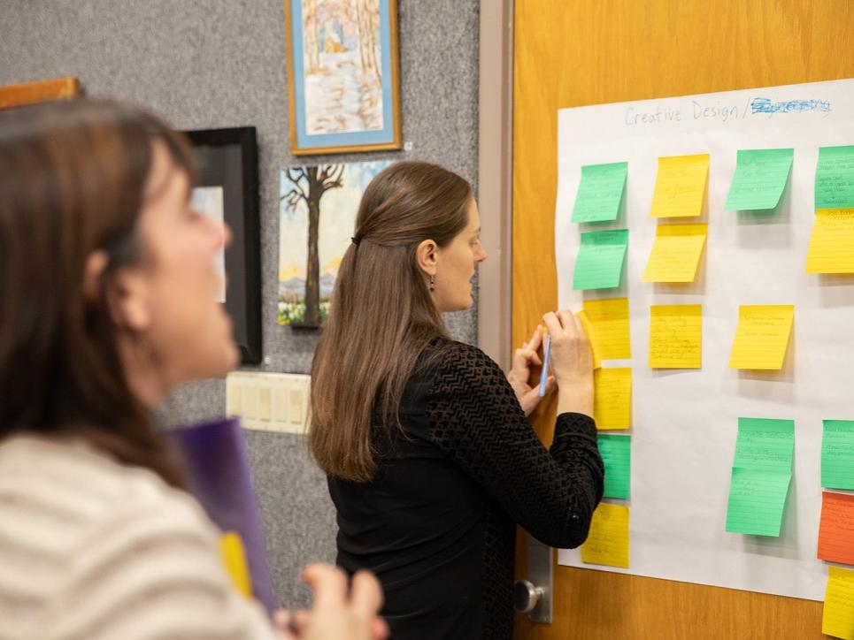 Woman puts post-it note on paper
