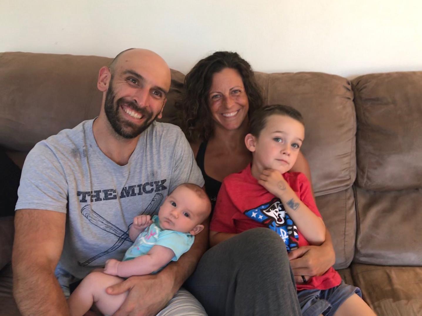 A man holds a baby girl, while a woman holds a young boy for a casual family photo