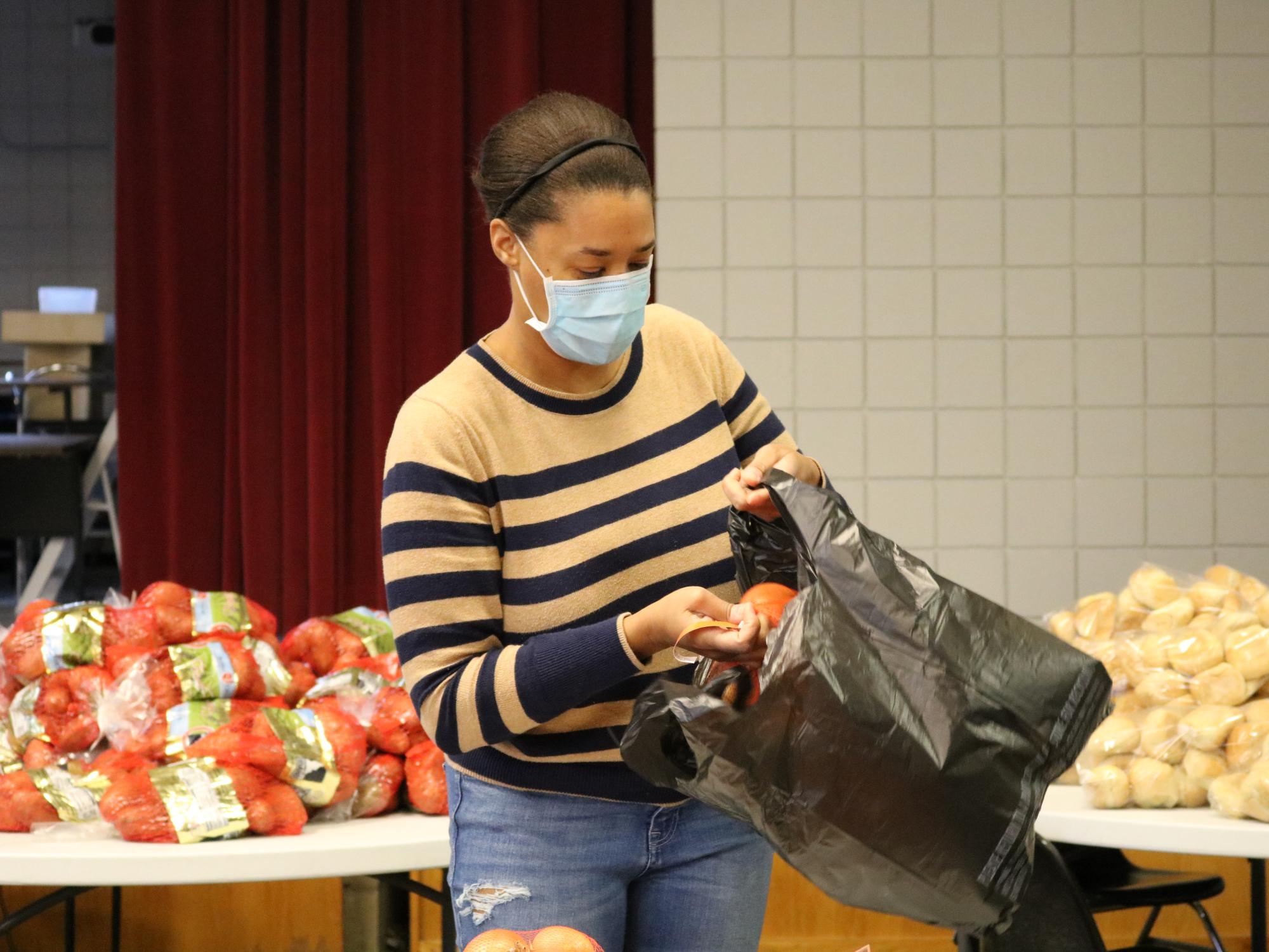 Woman placing onions in a plastic bag. 