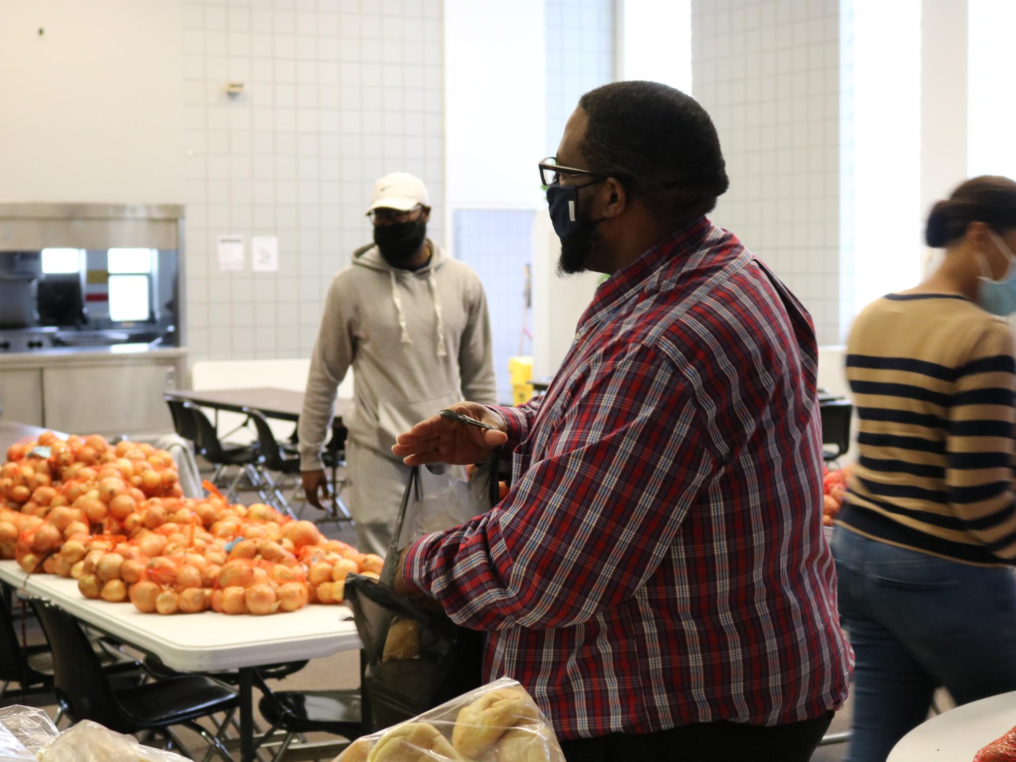 Man placing a packet of dinner rolls in a bag. 