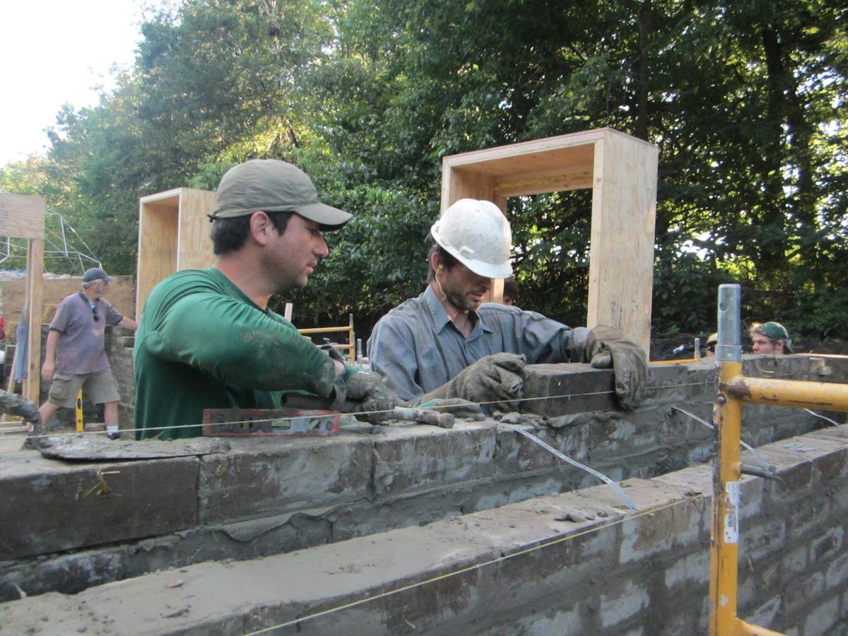 Marcin Jakubowski and a participant building a wall from Compressed Earth Blocks (CEBs)