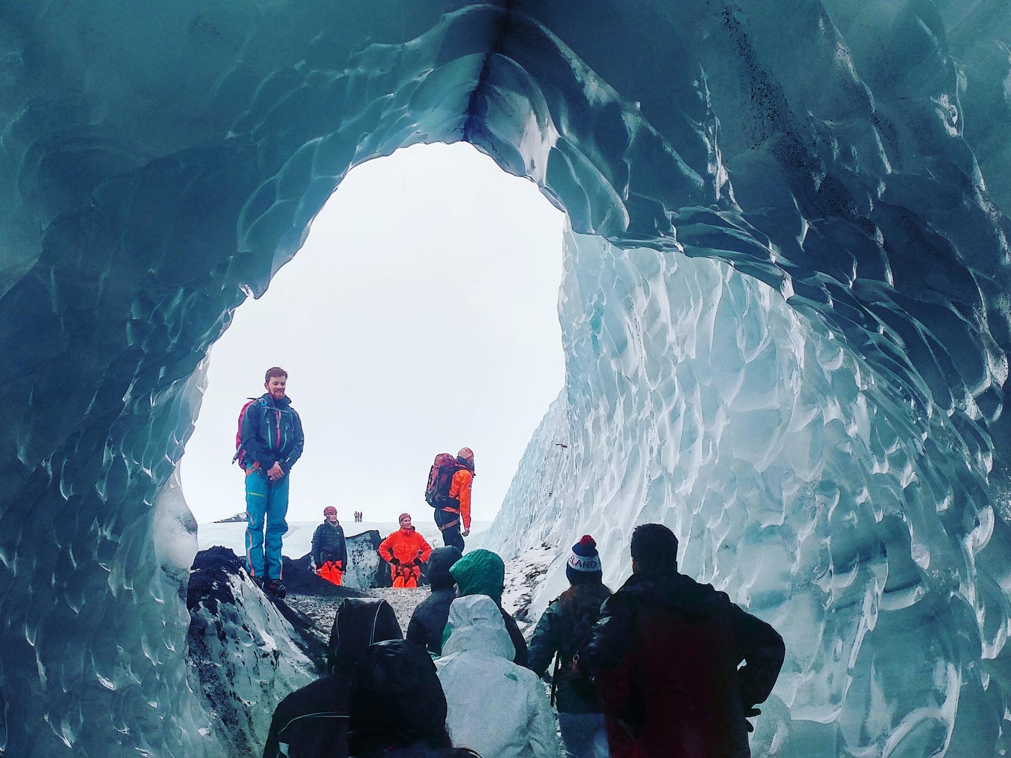 Tour guide shows students through the blur, dimpled ice tunnel.