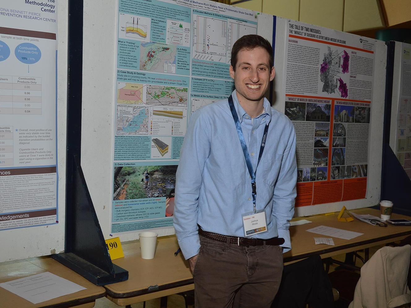 Joshua Woda, geosciences graduate student, stands next to his research poster