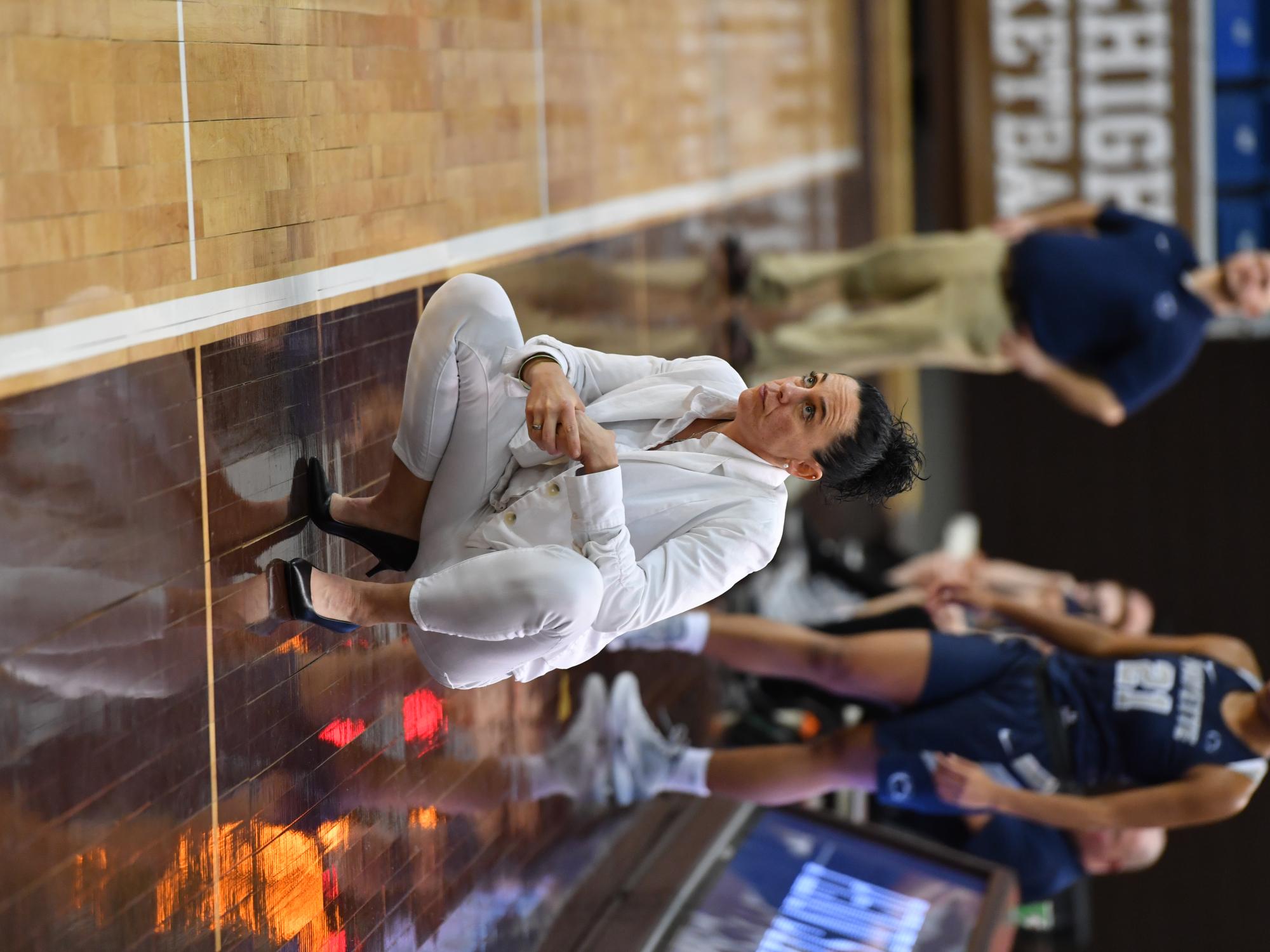 A women squatting on the sideline of a basketball court