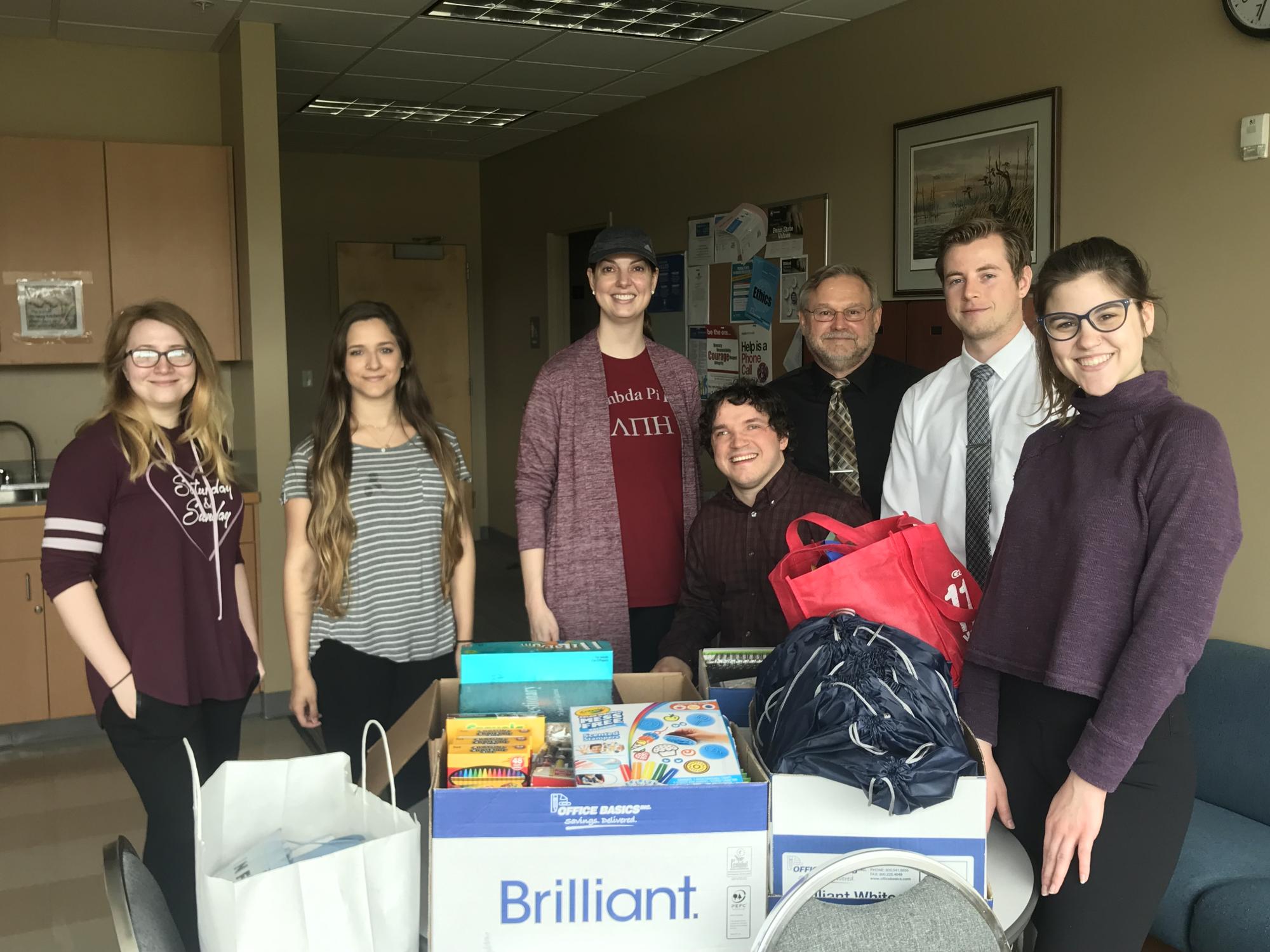 group photo of students and instructor with donation items