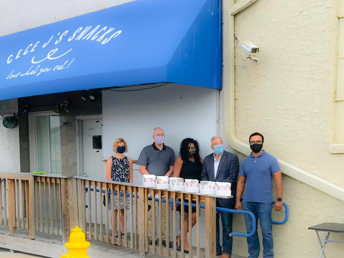 five people posed in front of a blue awning