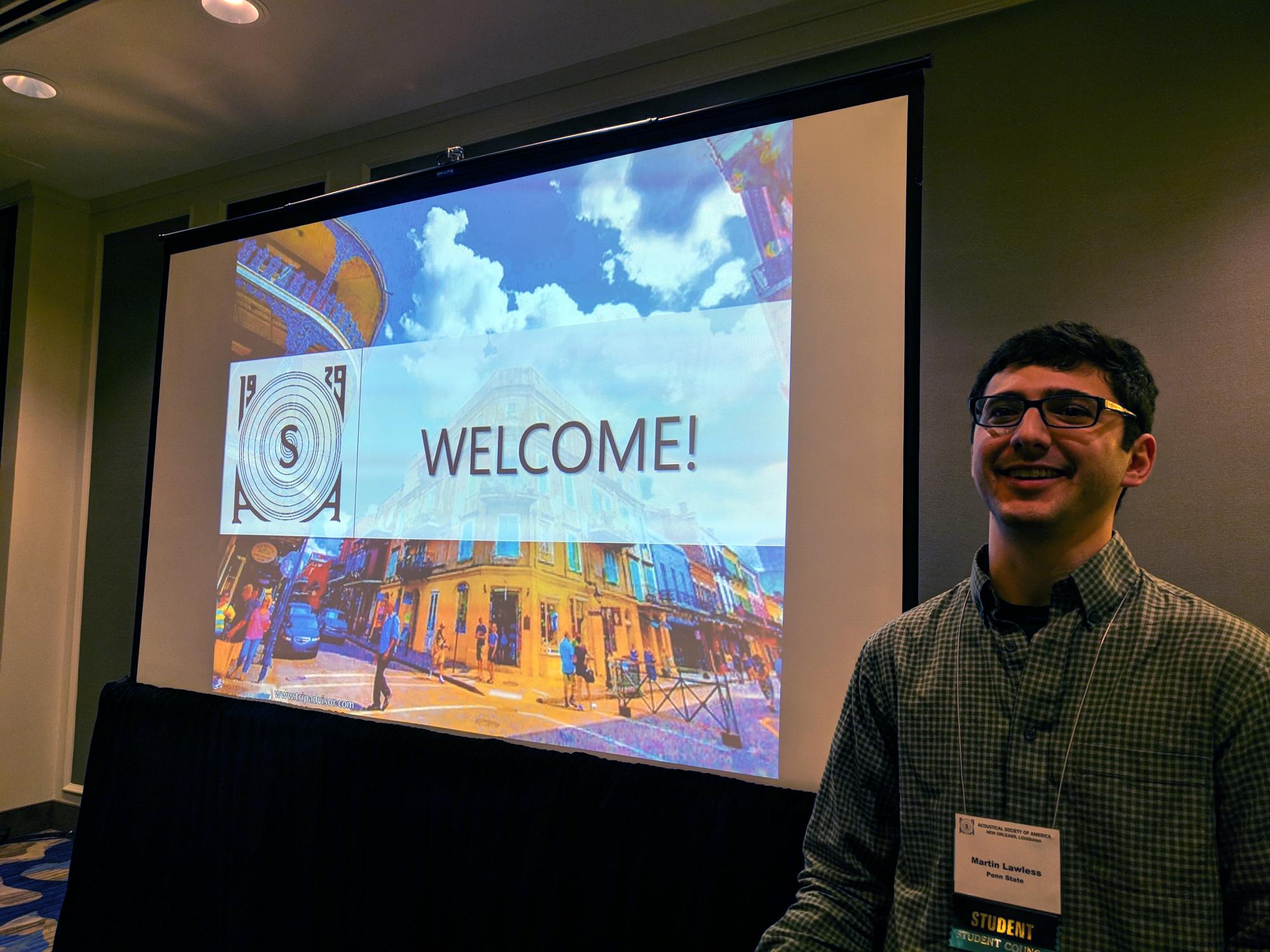 A graduate student welcomes other students to a conference
