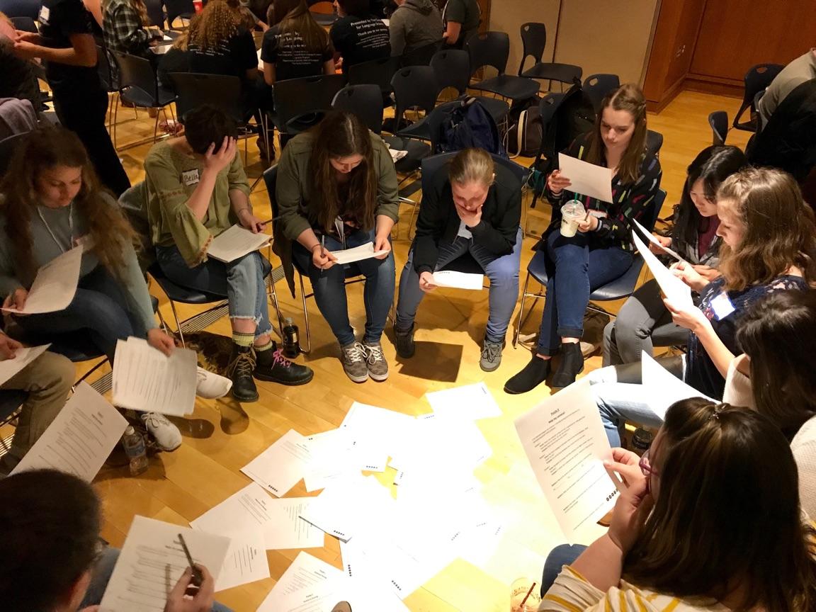 A team of students sits in a circle reviewing papers