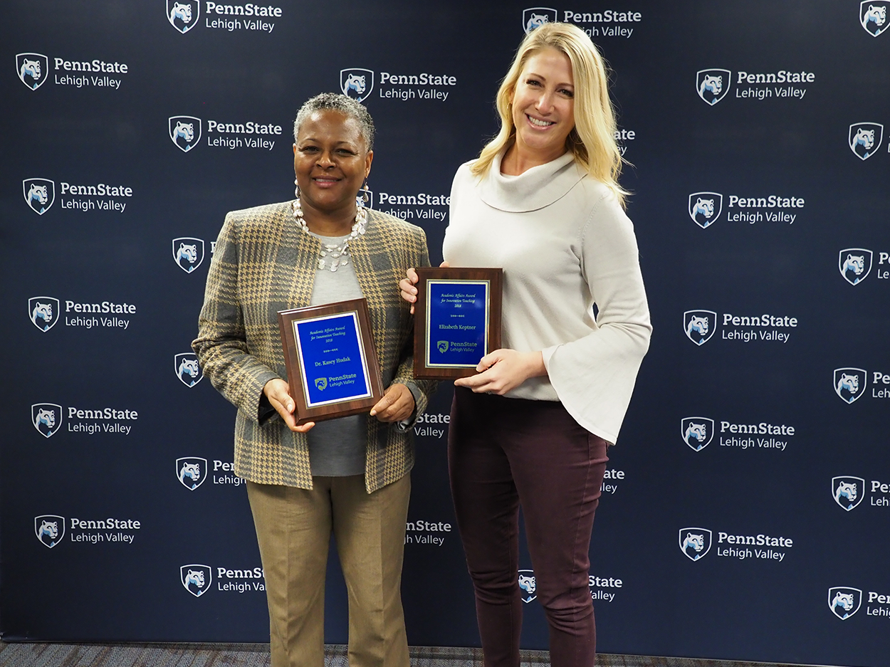 two women each holding a plaque