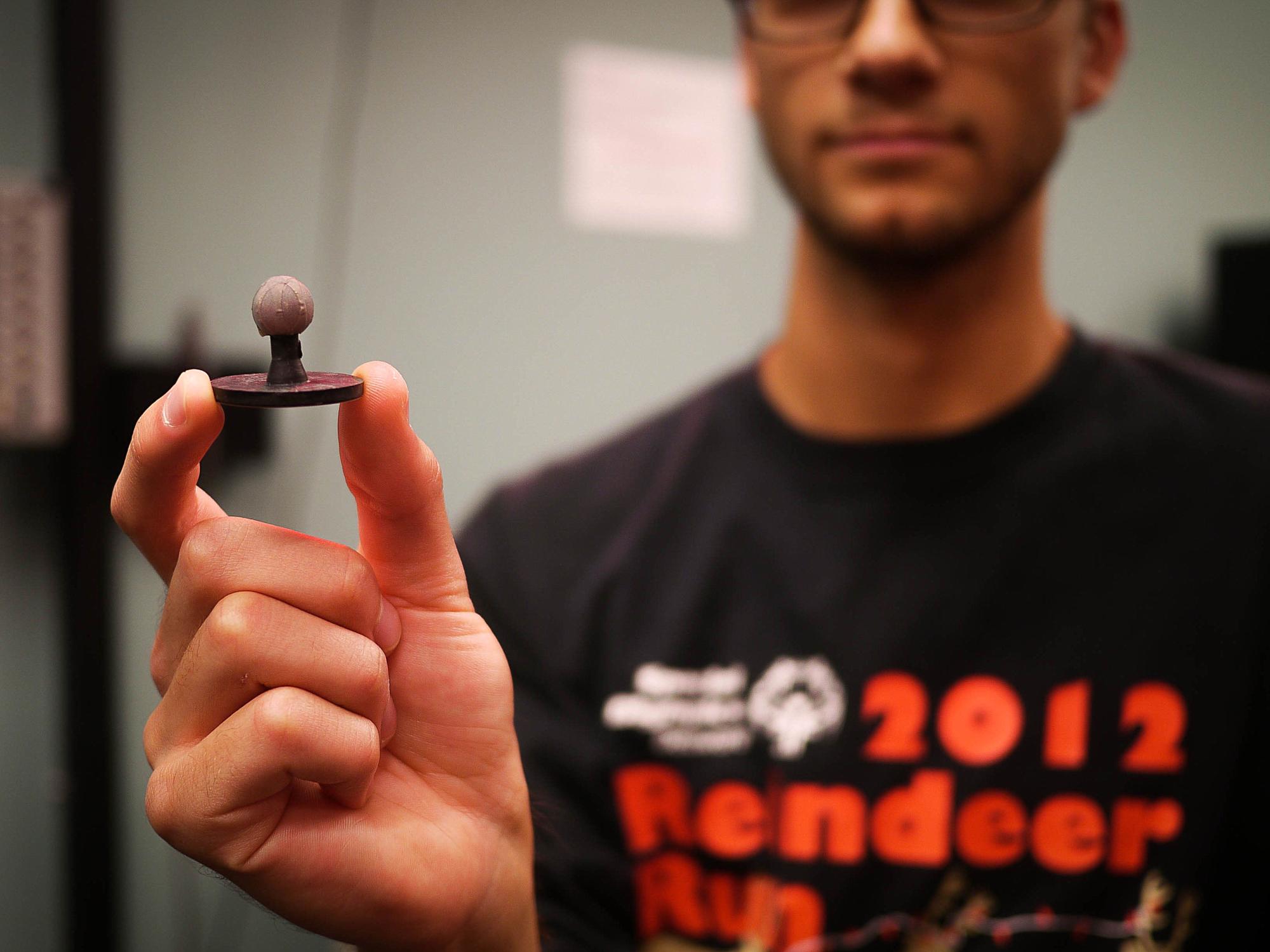 A student holds up a reflective piece of plastic called a marker, which is used in motion capture analysis
