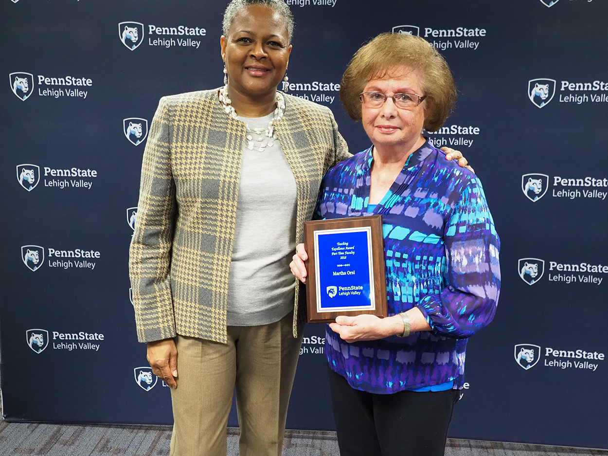 a woman handing a professor a plaque