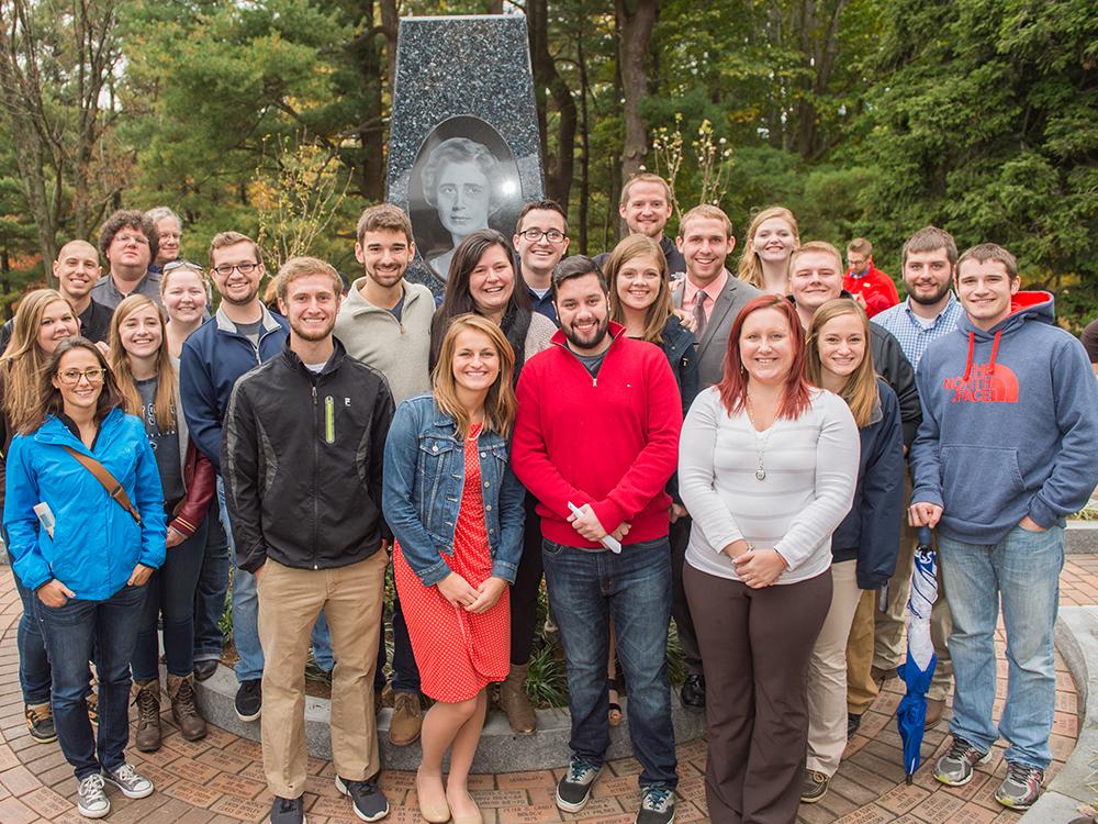 Students and alumni pose at the Mary Behrend monument.