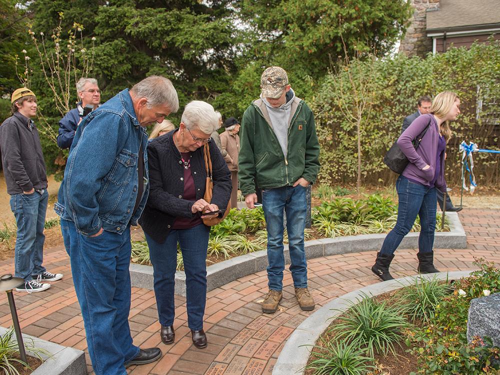 Alumni look for engraved pavers at the Mary Behrend monument.