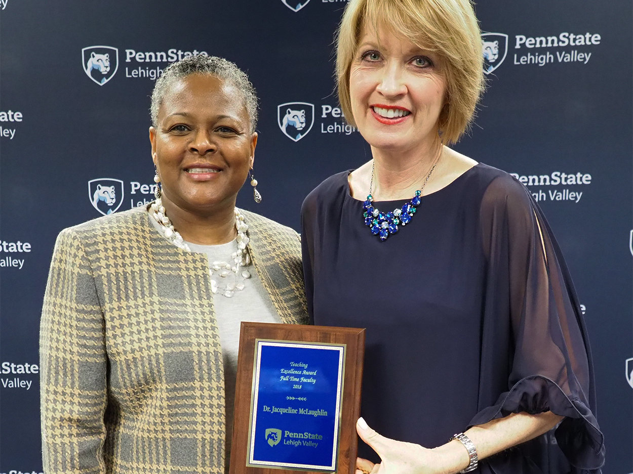 a woman handing a professor a plaque
