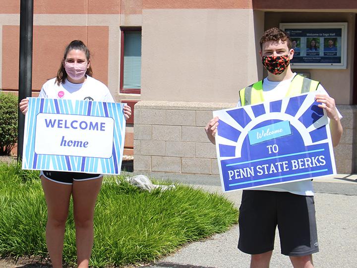 Orientation Leaders hold welcoming signs for incoming students.