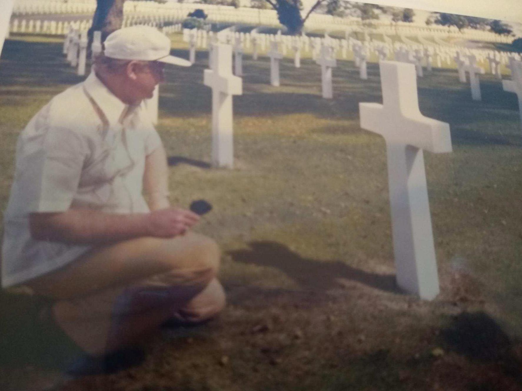 Man at grave in front of cross