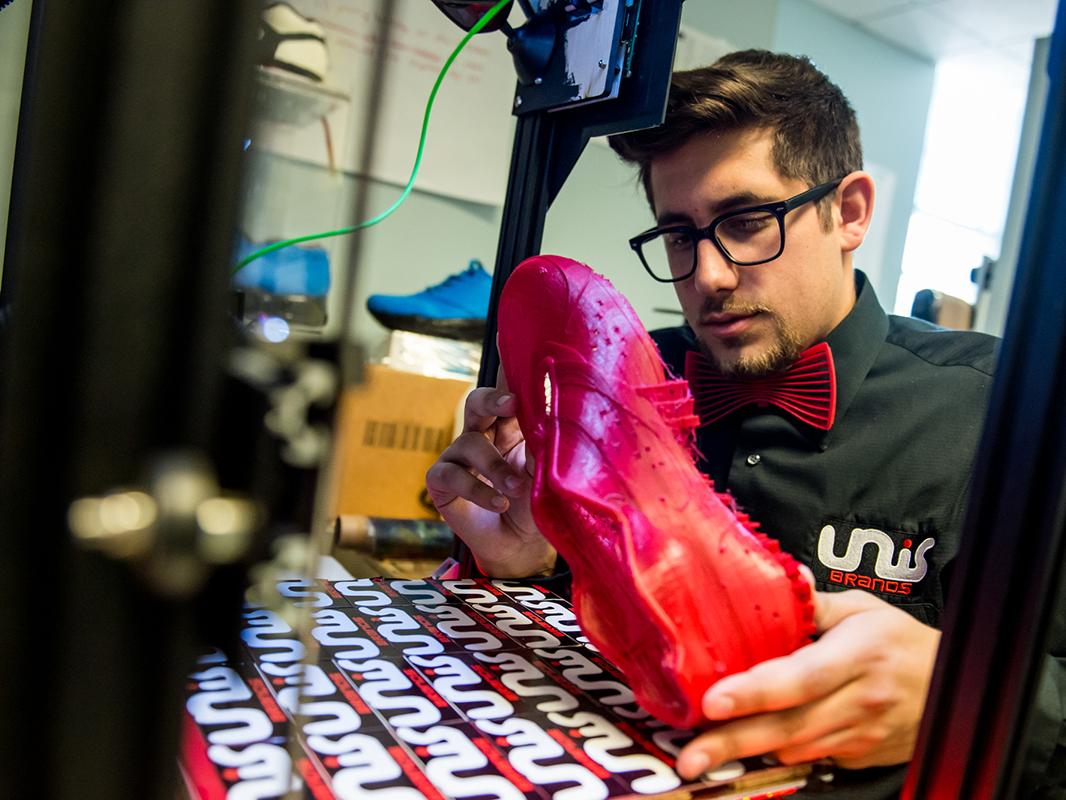A photo of Nicholas Unis inspecting a prototype of his 3D printed shoe