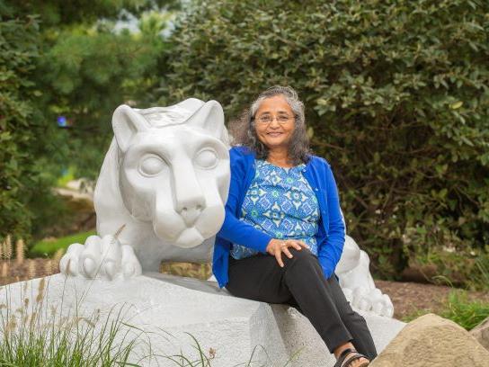 Alumna Nishi Gupta sits at the Nittany Lion shrine at Penn State Behrend