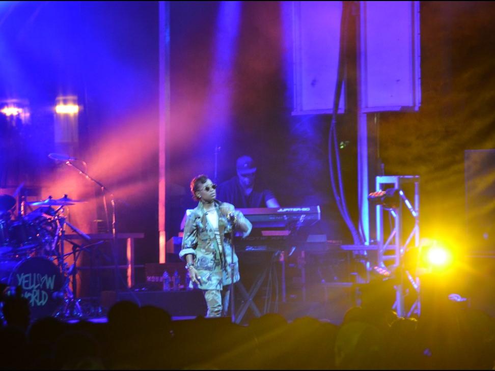 A performer stands on stage with colorful lighting
