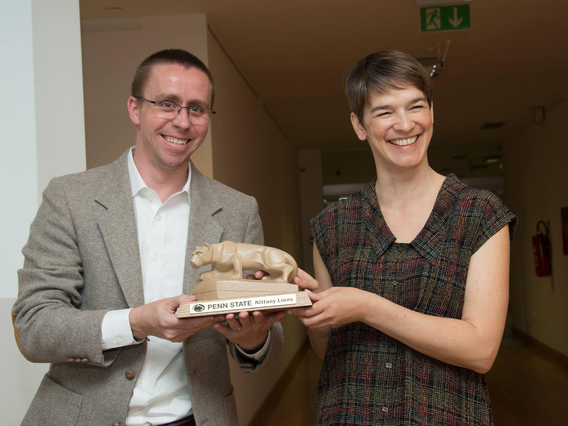 A man presenting a Nittany Lion statue to a woman.