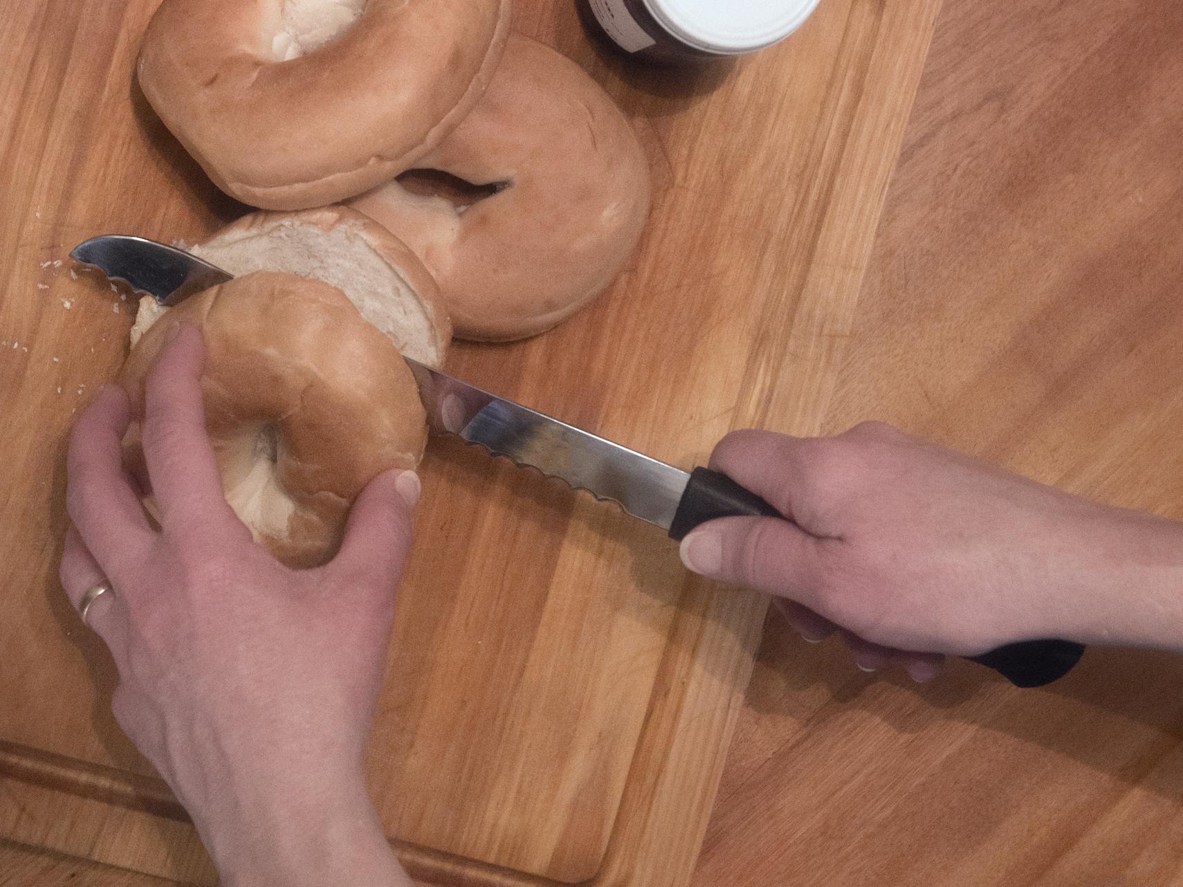 hands cutting a bagel in half