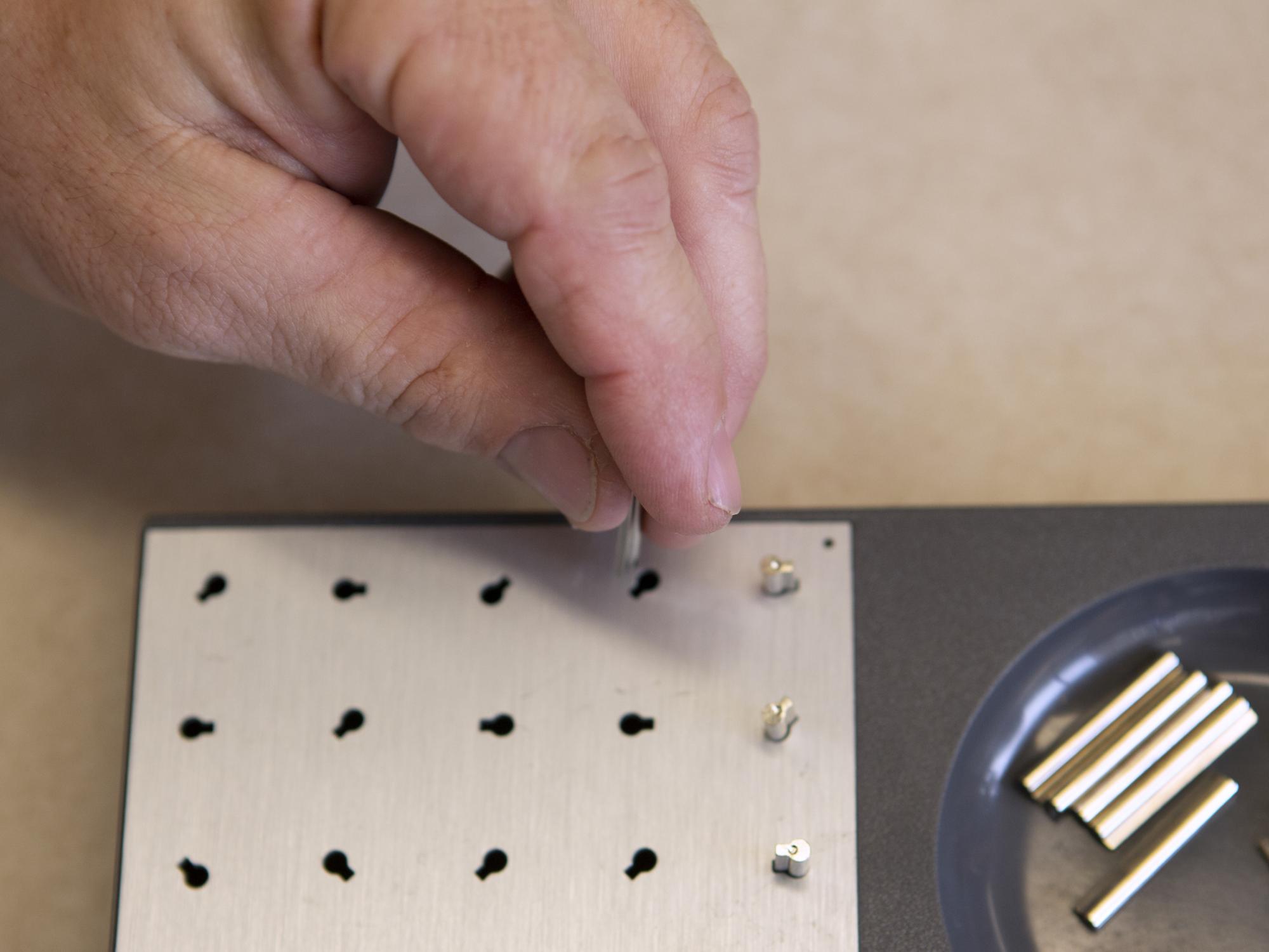 close-up of hand putting tiny peg into hold