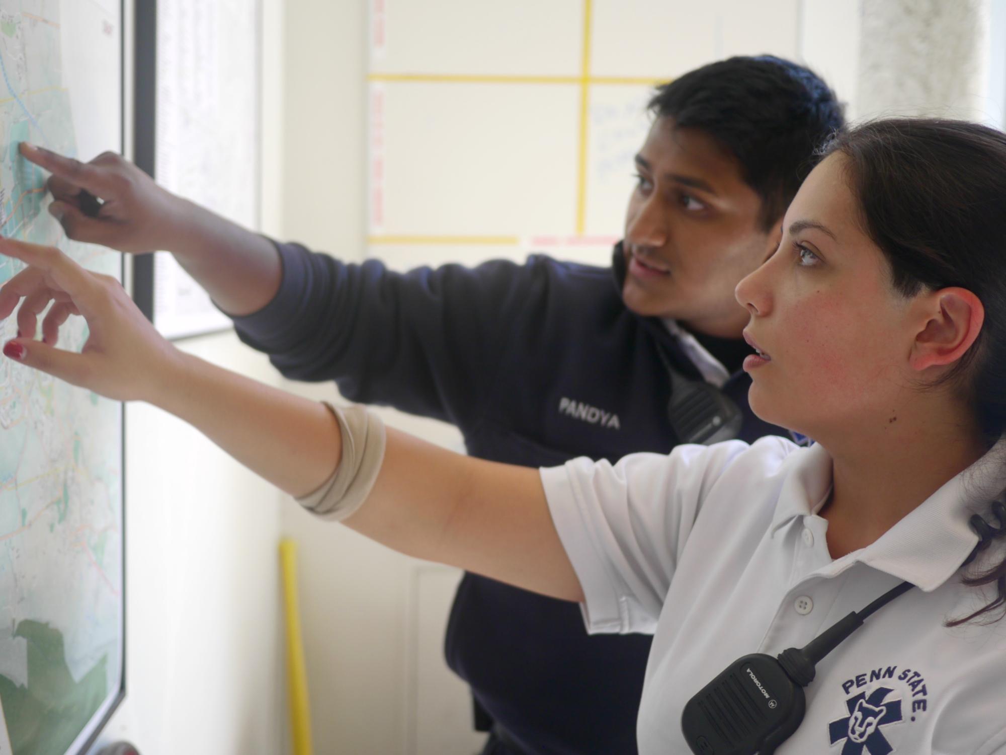 EMTs Ravi Pandya and Nicolle Frey review a map of Centre County posted in the ambulance hub. 