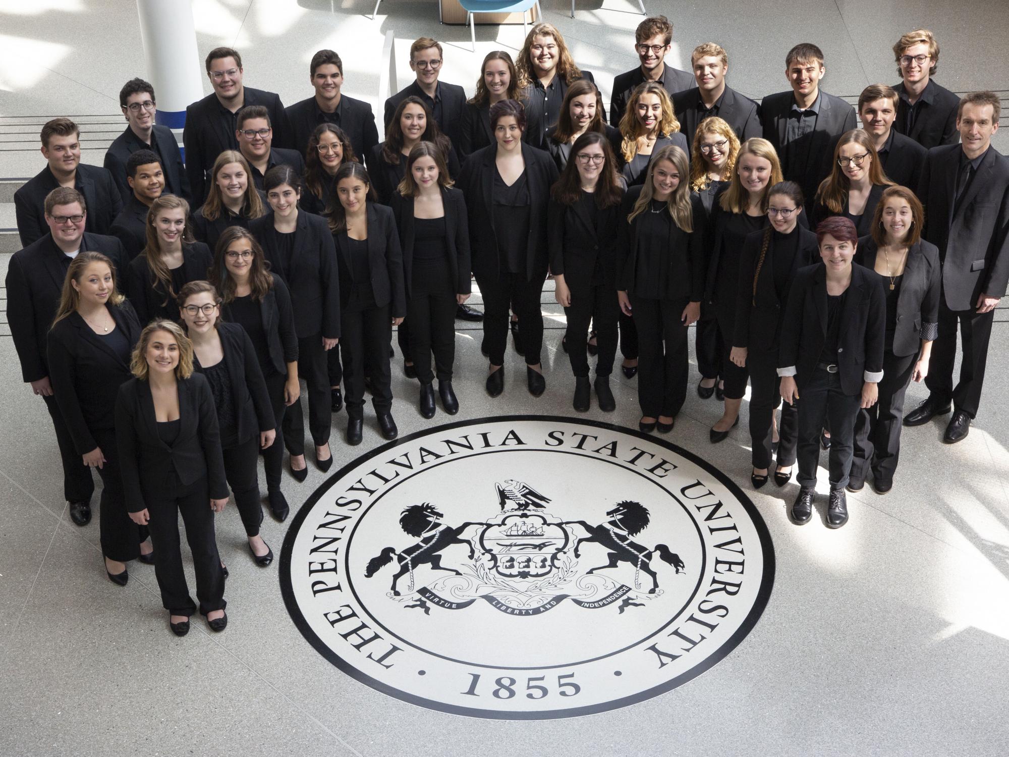 A group of students stand and look up for a group photo.