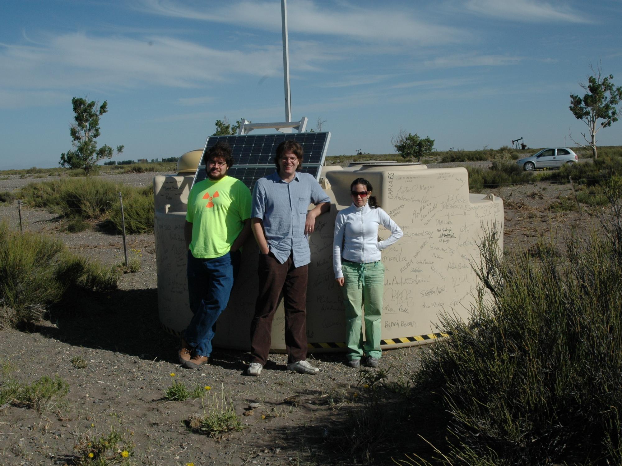 Three students from Miguel Mostafá's lab, standing in front of the 1600th detector installed as a component of the large Pierre Auger Observatory array in western Argentina.