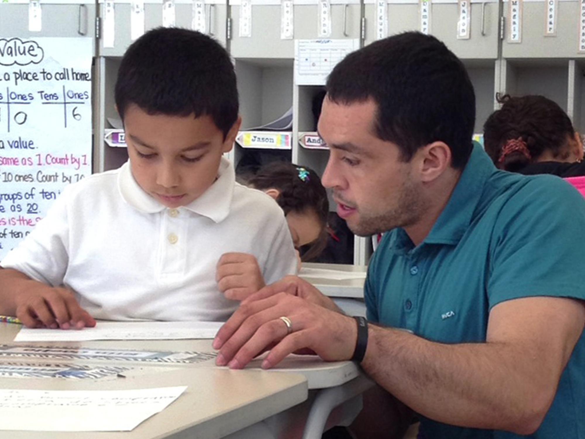 Penn State alumnus and Teach For America teacher Sergio Santiago looks over an assignment with a student