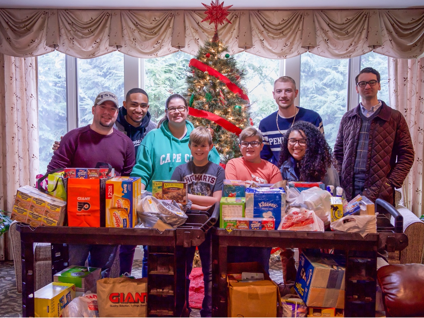 people seated and standing with Christmas tree