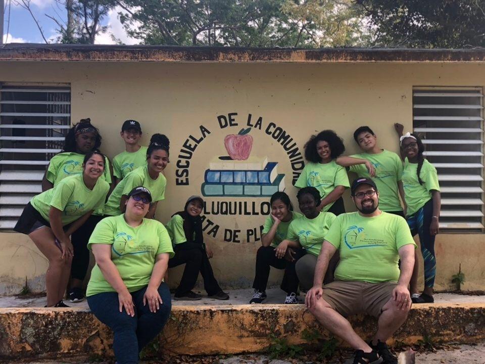 students pose in front of school