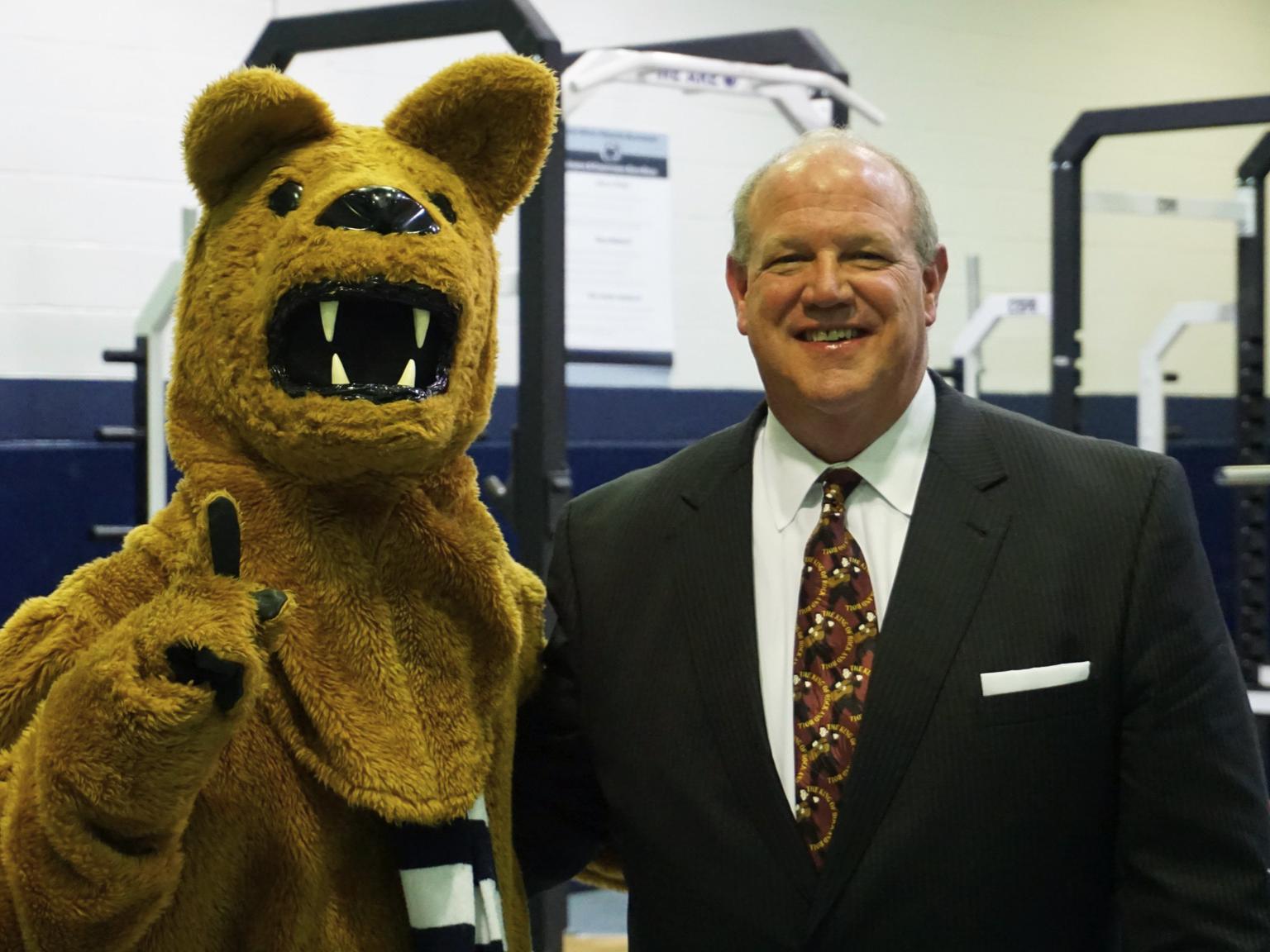 Regis W Becker standing next to Nittany Lion mascot
