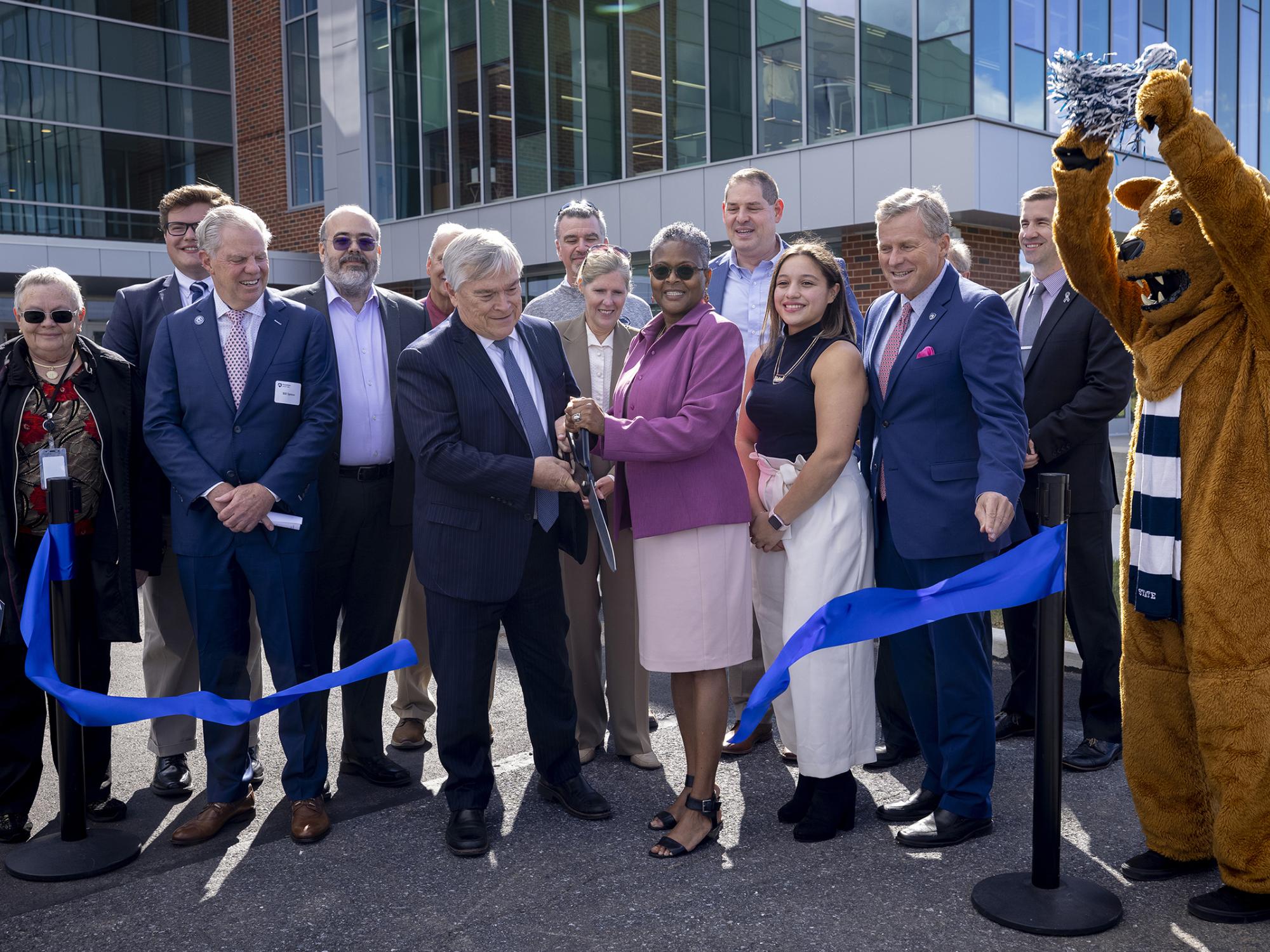 Penn State President Eric J. Barron and Penn State Lehigh Valley Chancellor Tina Q. Richardson cut a blue ribbon while standing in front of the new PSU-LV expansion.