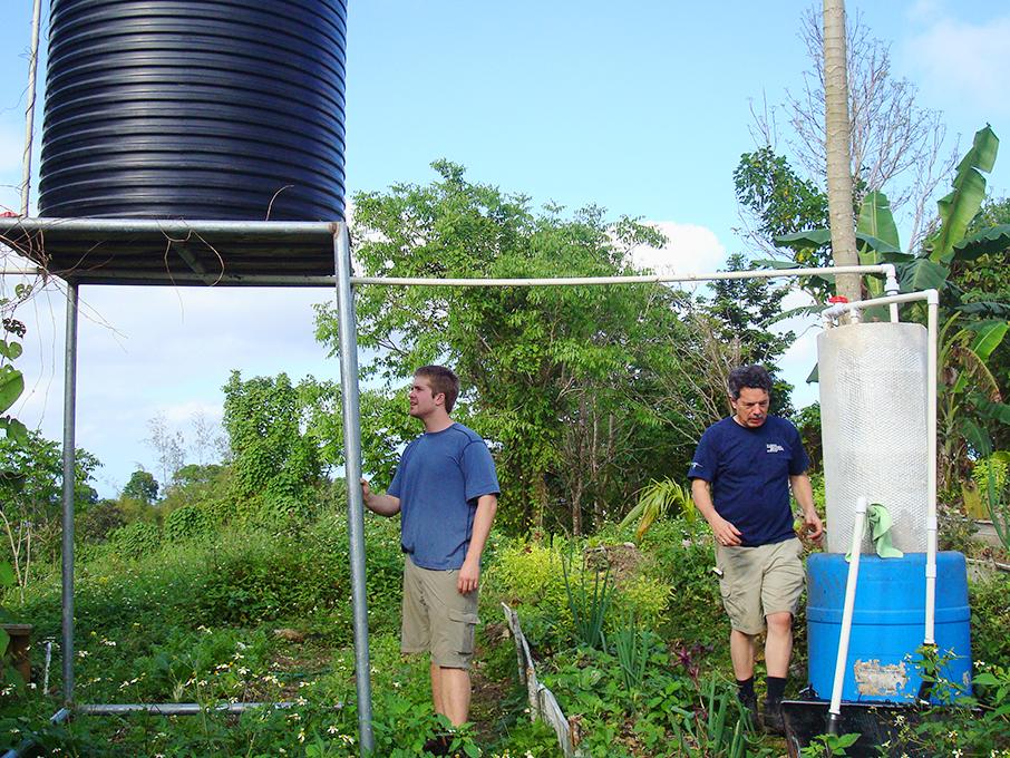 Tim Robinson, who is retiring on June 30, helps William Atcheson, an energy business and finance graduate, install a solar water heater in Jamaica. 