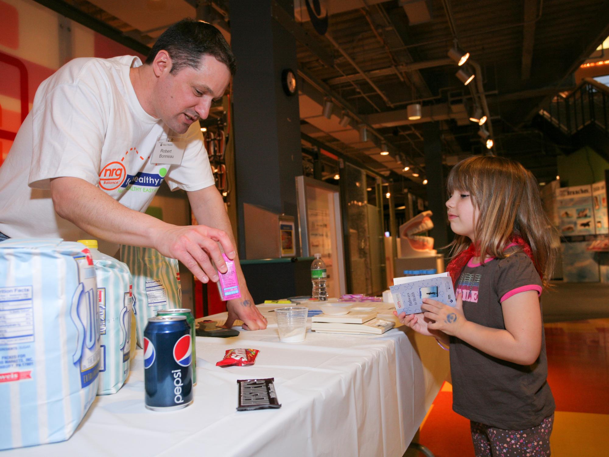 Dr. Rob Bonneau interacts with a young girl at a spring community engagement event on topics related to health and wellness in 2009.