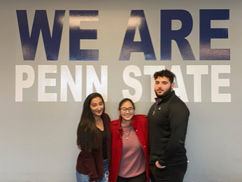 three students under We Are Penn State sign