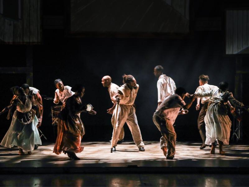 A group of dancers hunker down while they form a circle.