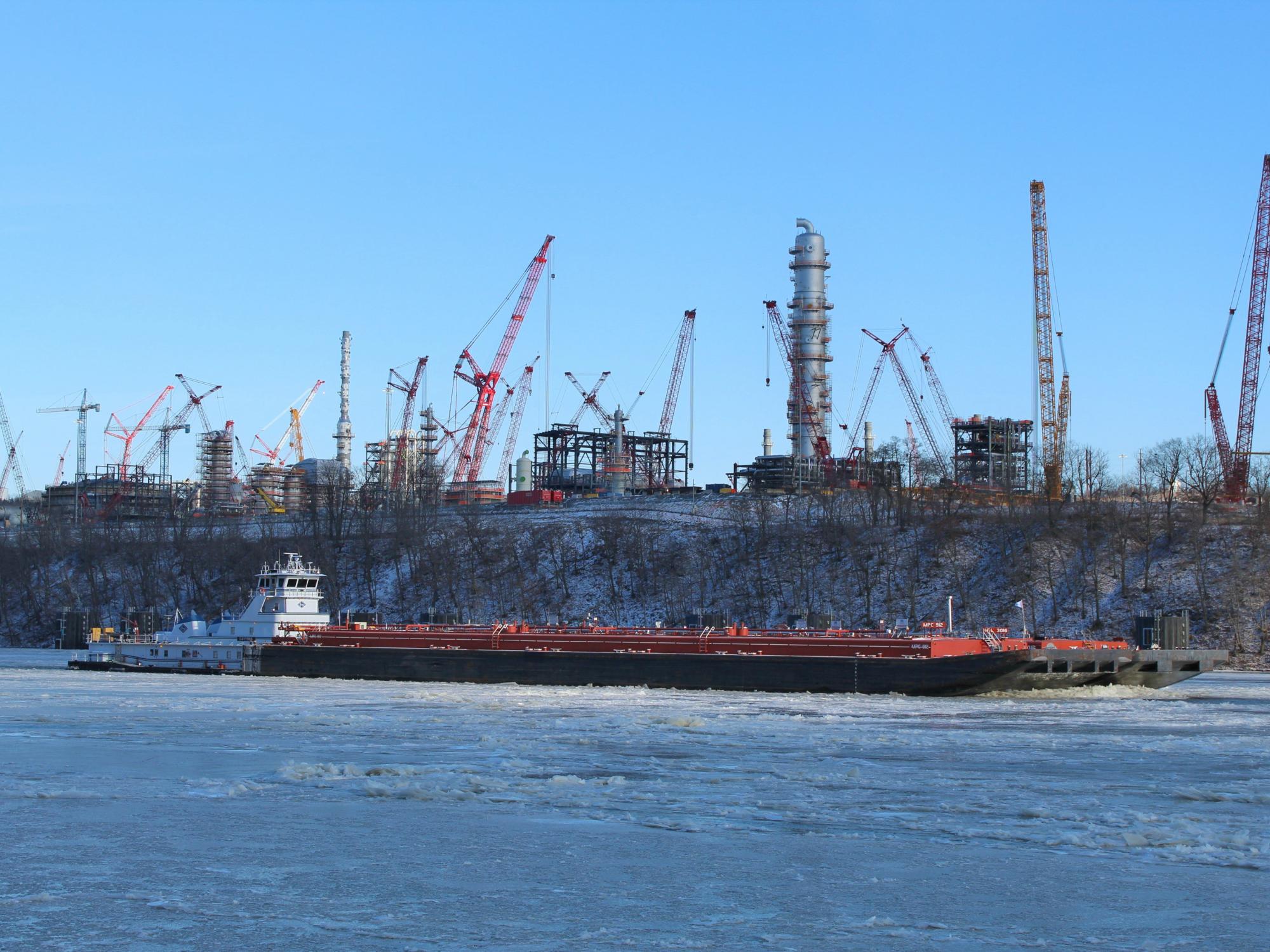 A boat pushes a barge down the Ohio River, which flows by the Shell Pennsylvania Petrochemicals Complex.