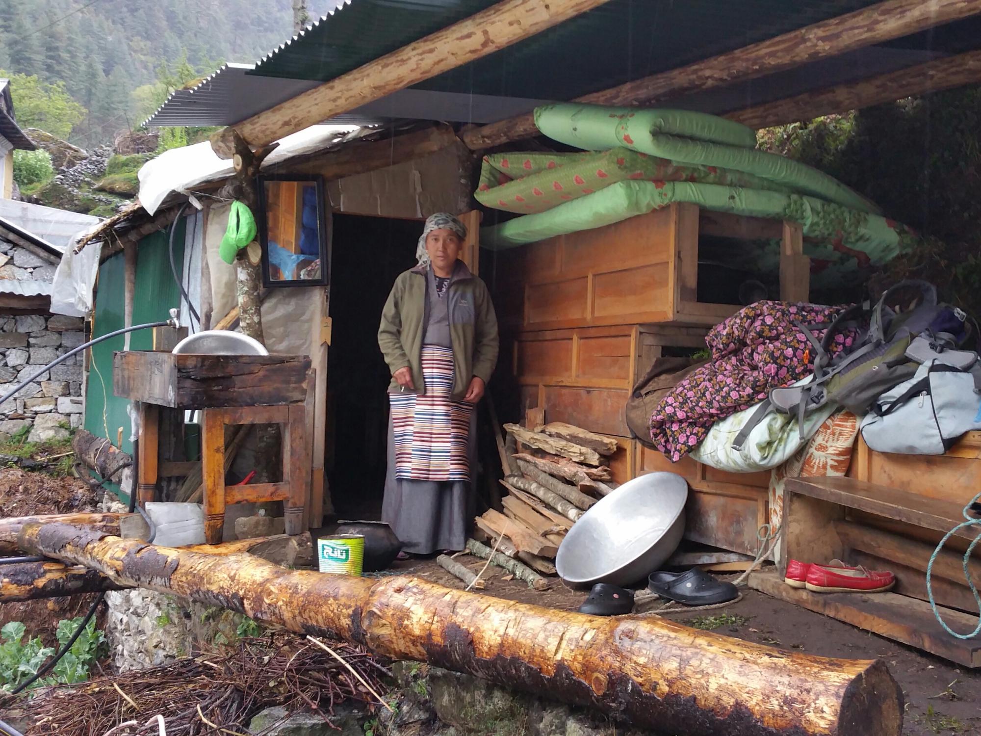 A woman stands in front of a makeshift shelter in Nepal