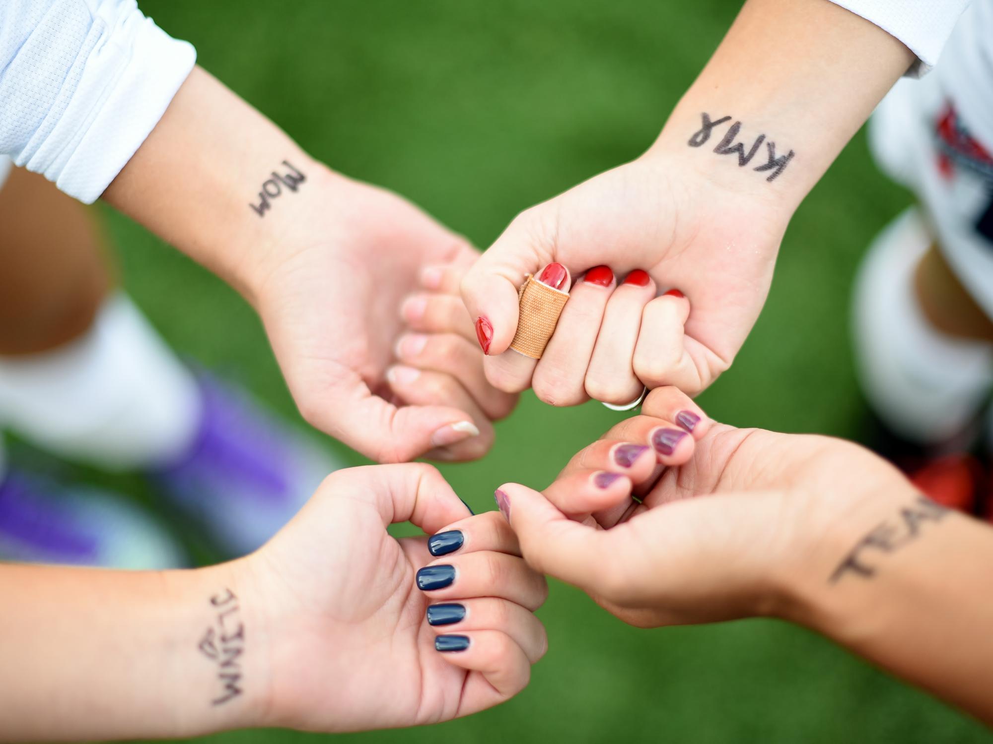 Four Penn State Behrend soccer players show motivational words they have written on their wrists.