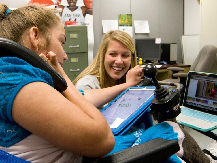A graduate student works with a young student at an elementary school to do speech therapy.