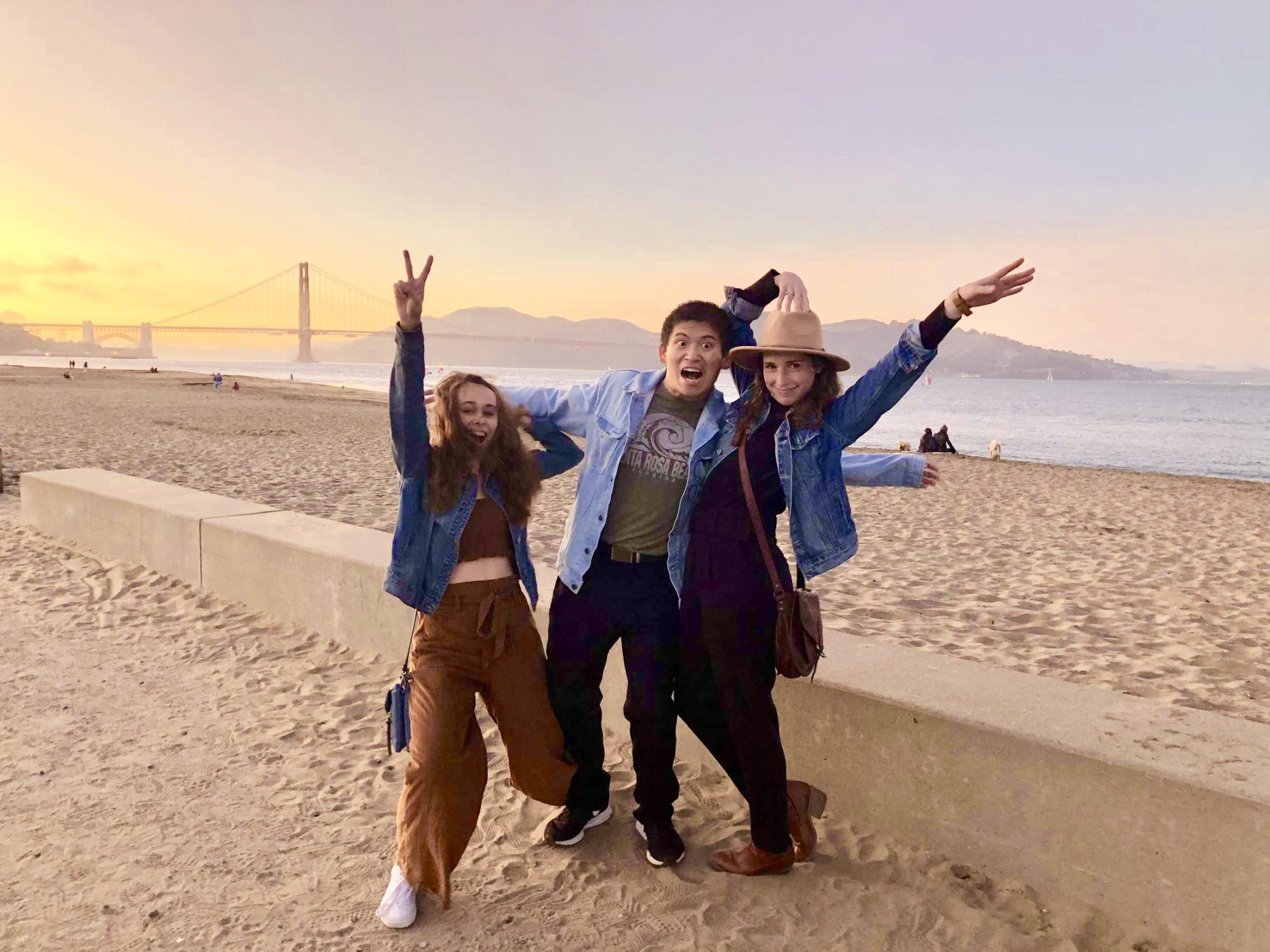 Three students make fun poses while standing on the beach in front of the Golden Gate Bridge in San Francisco, CA