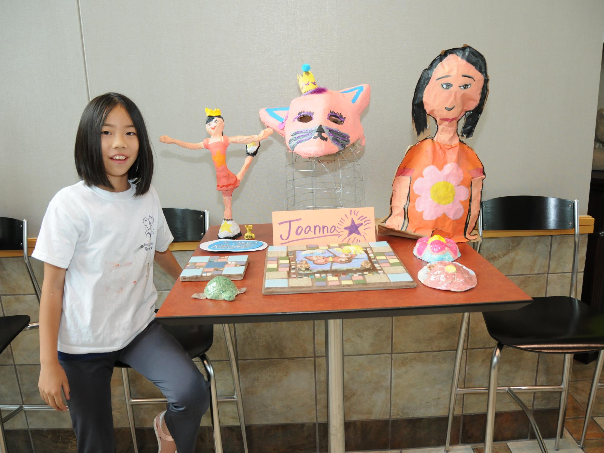 A youth camper displays the artwork made during her camp.