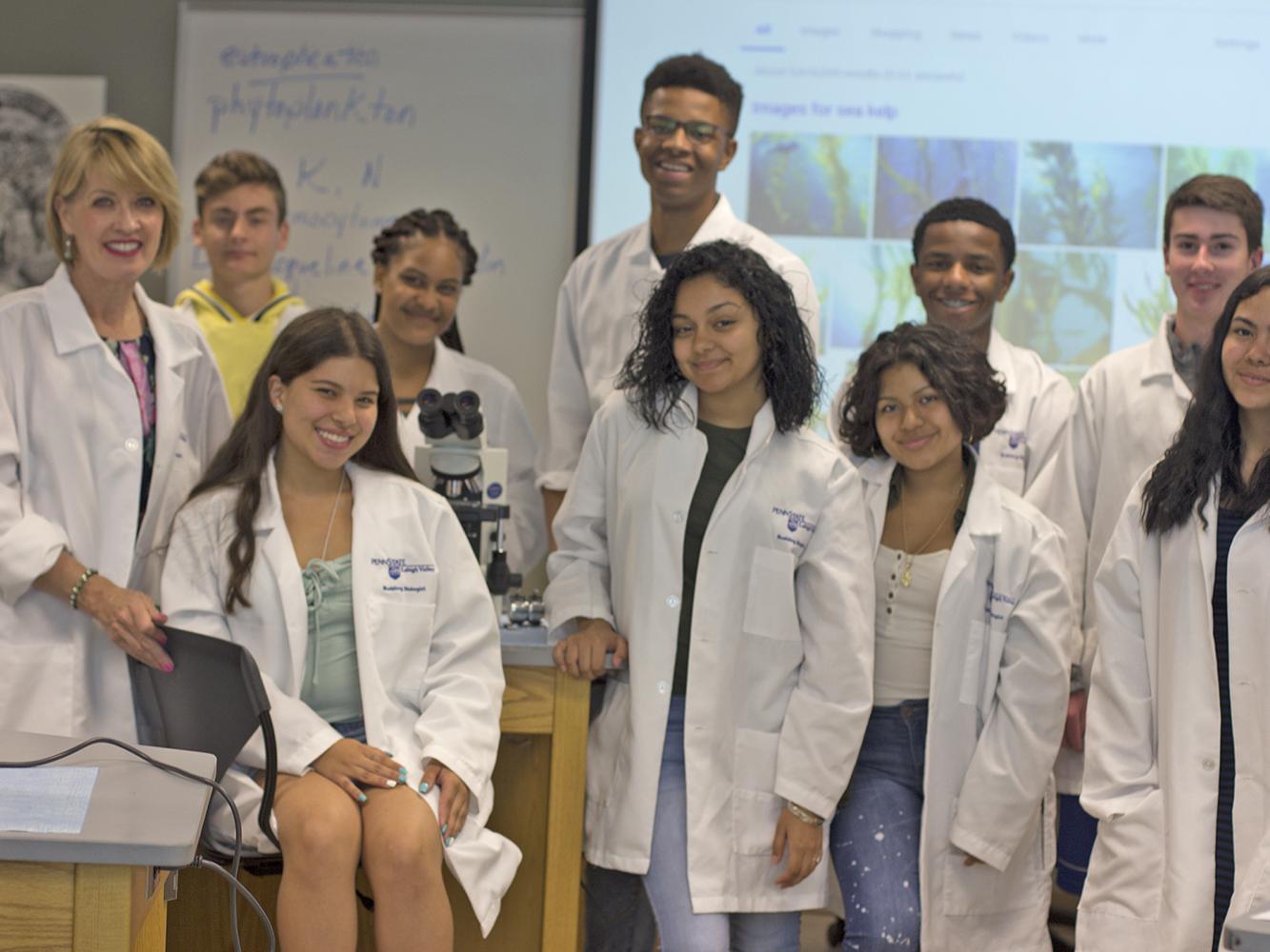 campers in lab coats in a lab with professor