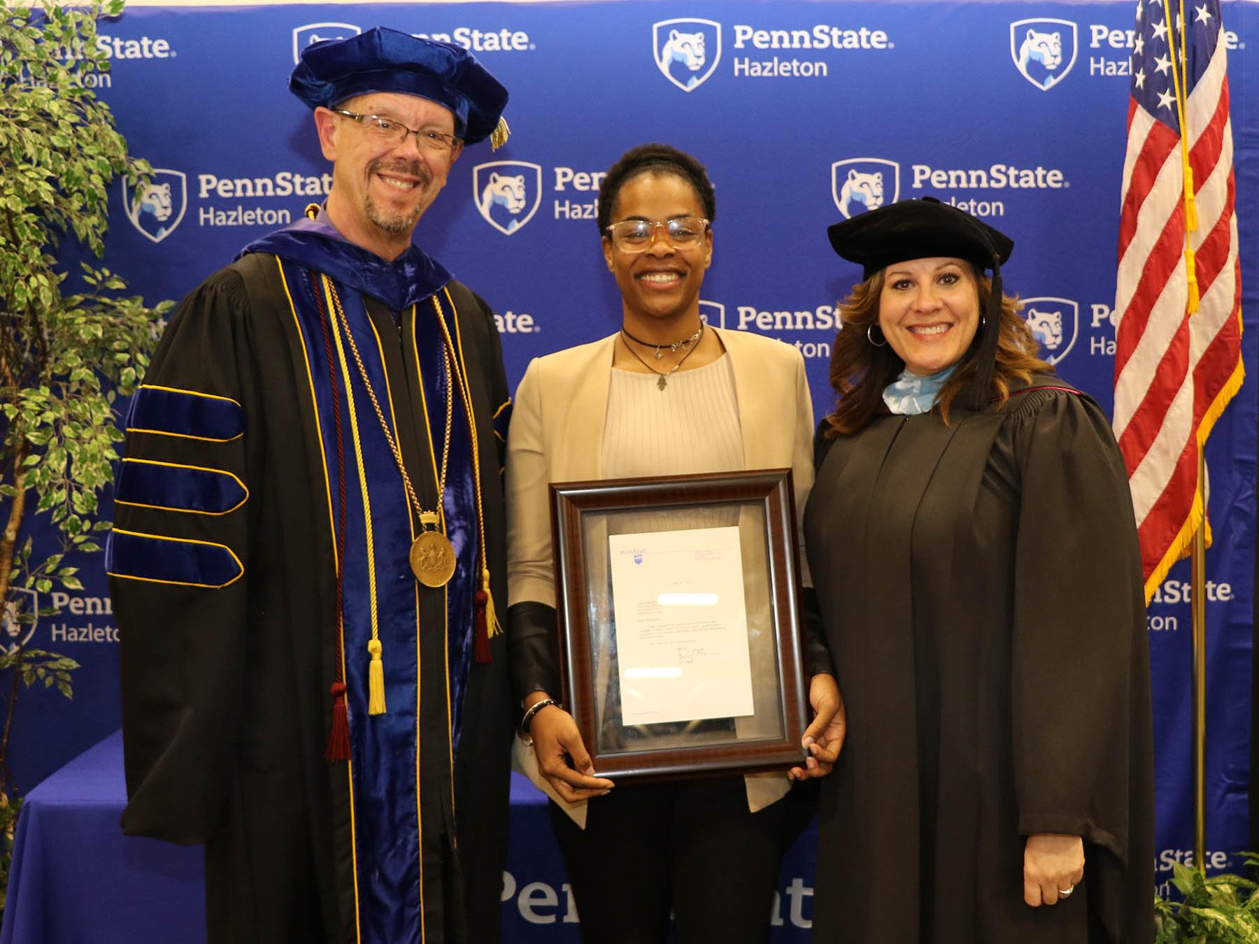 Student award winner standing with campus administrators