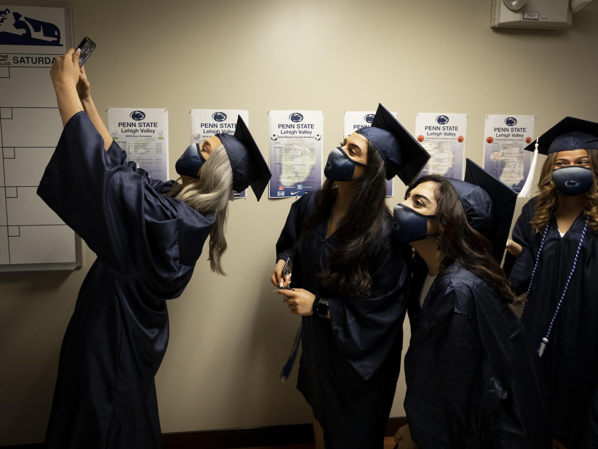female women in cap and gown lining up for selfie photo